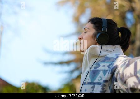 Woman wearing headphones with eyes closed listening to music in a park Stock Photo