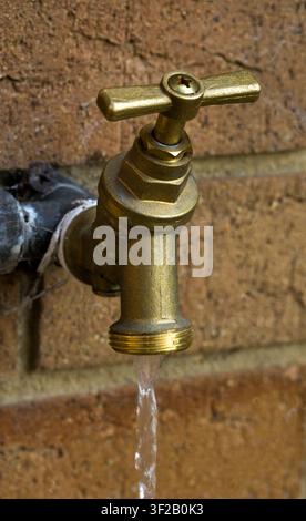 Outside Tap with Running Water on Garden Wall Stock Photo