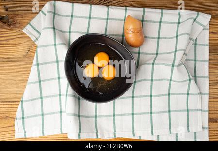 Two Broken Eggs in Bowl , Raw Yolk and White, Fresh Broken Organic Chicken Eggs on White Napkin Background Stock Photo