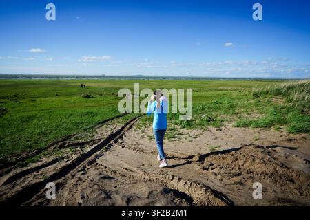 A person walking on a dirt path through a grassy field. Stock Photo