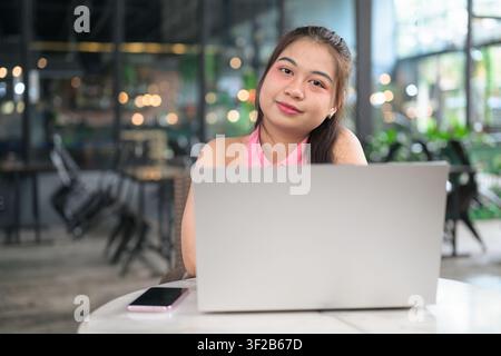A horizontal medium shot of a charming Southeast Asian Thai Isan woman tilting her head slightly and smiling pleasantly at the camera behind her open Stock Photo