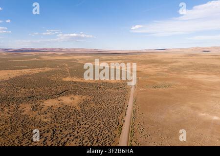 Aerial drone view of Smoke Creek Road stretching through the vast sagebrush high desert of Lassen County, California near the Nevada state line. Stock Photo