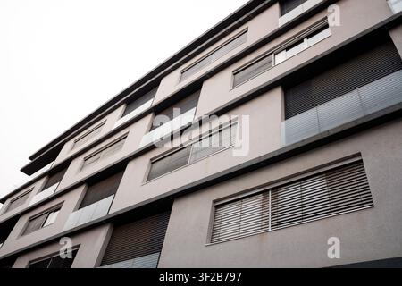 Apartment building showing geometric design, windows, and closed shutters Stock Photo