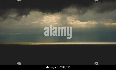 Aerial view of dramatic sunbeams breaking through dark storm clouds over the sea in Japan. Stock Photo