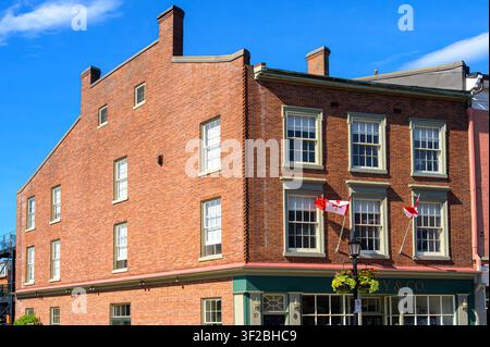 Historic red brick commercial building with Canadian flags and preserved nineteenth-century storefront Stock Photo