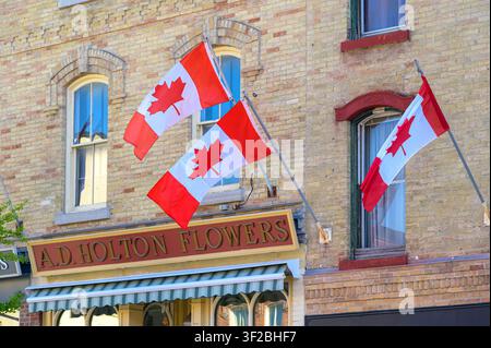 Three Canadian flags displayed above a historic flower shop A.D. Holton Flowers Stock Photo