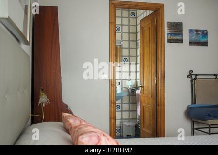 A close-up, angled view of an apartment bedroom focusing on a doorway. An open, traditional wooden door with classic hardware frames the view into a c Stock Photo