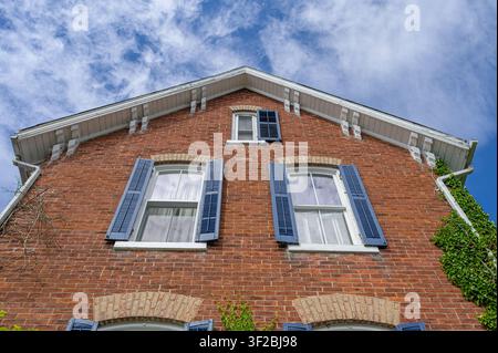 Red brick facade with blue shutters viewed from a dramatic low-angle perspective. Stock Photo