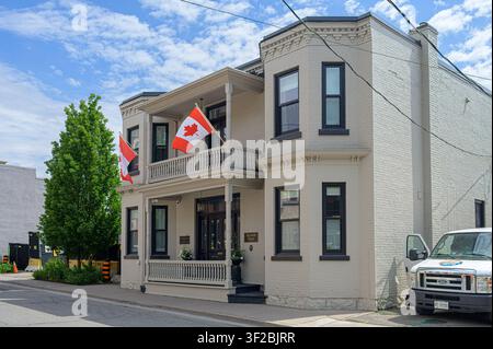 Colonial style house with Canadian flags, wraparound porches, and elegant painted brick exterior Stock Photo