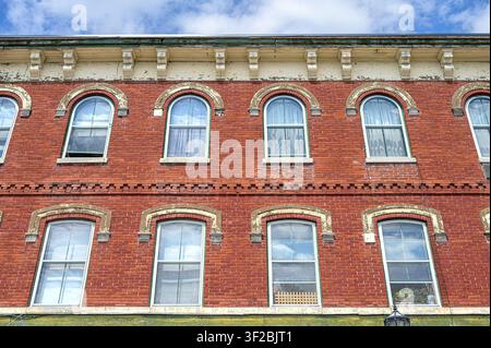 Historic red brick building facade with arched windows, decorative cornice, and classic architectural details Stock Photo