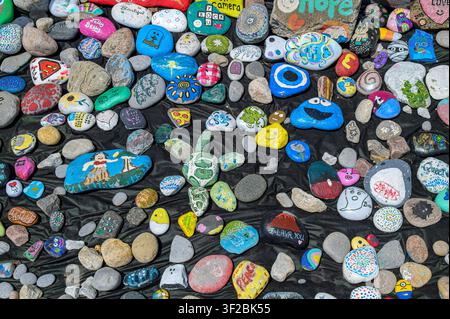 Colorful hand-painted rocks displaying creative artwork on a city corner and close to the Ganaraska River Stock Photo