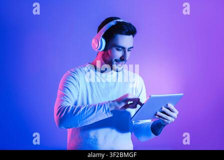 Happy man in wireless headphones uses tablet Stock Photo