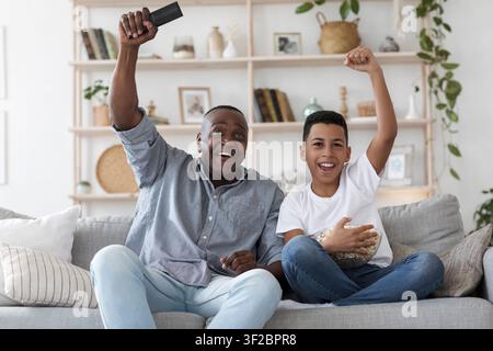 Leisure With Grandpa. Senior African Man Watching Sports On Tv With Grandson Stock Photo