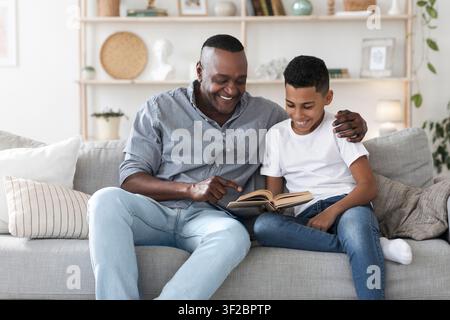 Mature african american man reading book with his grandson at home Stock Photo
