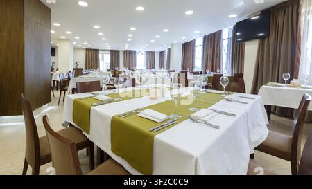 Large table in restaurant with white and green tablecloth Stock Photo