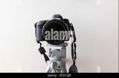 Front view of a Canon DSLR camera mounted on a tripod isolated against a white background Stock Photo