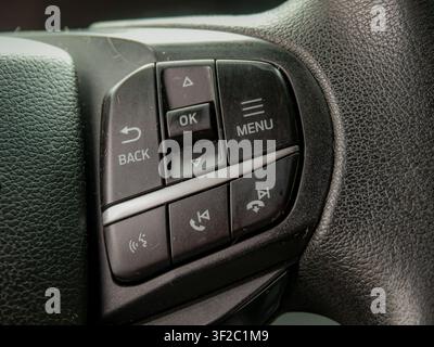 Macro close up shot of a modern car steering wheel audio and navigation control cluster with buttons for menu, back, and ok functions Stock Photo