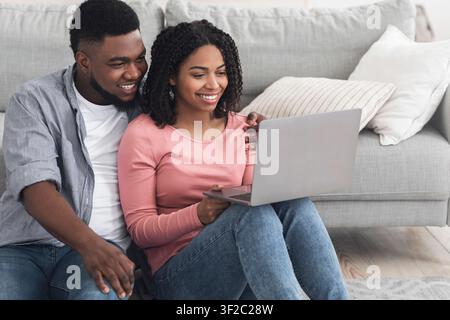 Work From Home. Smiling African Couple Using Laptop, Working Online Together Stock Photo