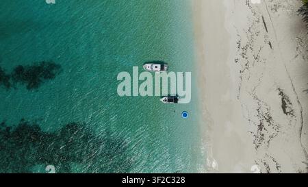 Aerial view of Rose Island with two boats anchored in clear turquoise water near a white sandy beach in New Providence, The Bahamas. Stock Photo