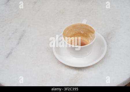 Cup sits empty on a white table after enjoying coffee Stock Photo
