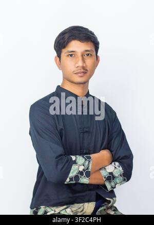 Portrait of a confident Asian man wearing traditional Cheongsam batik fusion shirt posing on a white studio background. Stock Photo