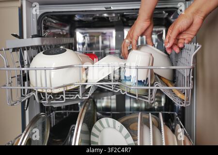 Placing clean dishes in the dishwasher after washing Stock Photo