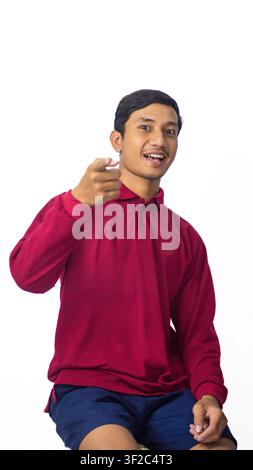 Smiling Asian male model wearing traditional shirt showing pointing forward on white studio background. Stock Photo