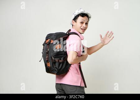 happy asian man backpacker greeting with open palm. digital nomad and travelling concept. on isolated background Stock Photo