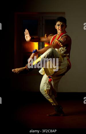 A skilled Indian classical dancer in traditional attire performs an expressive dance pose. The vibrant colors and intricate costume details highlight Stock Photo