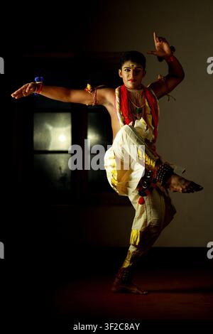 A traditional Indian dancer in a vibrant costume, striking a dynamic pose. The captivating expression and dramatic lighting capture the essence of cul Stock Photo