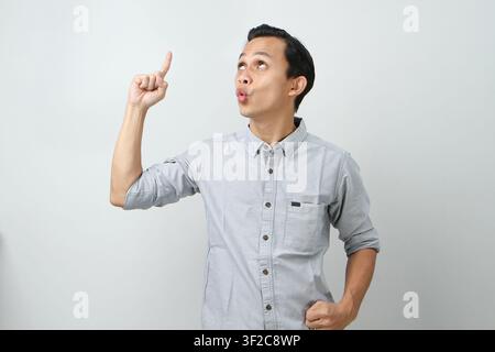 Funny happy cheerful asian indonesian man expression pointing finger up his head on isolated background Stock Photo