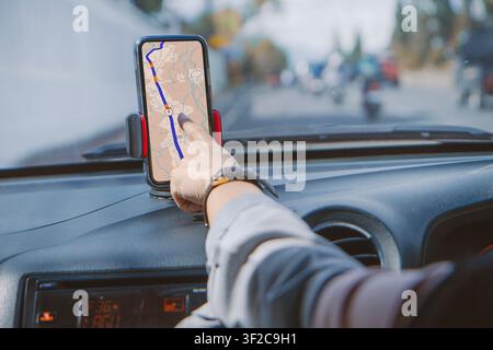 Driver using GPS navigation in mobile phone while driving car. Woman driving while using the mapping app on his smartphone to find his location. using Stock Photo
