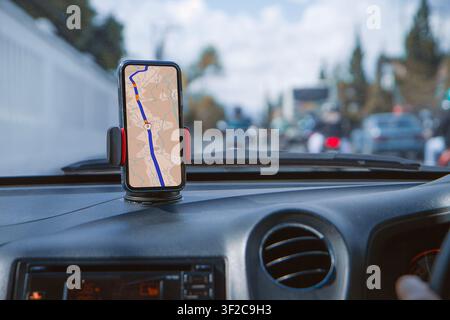 Smartphone with navigation route on screen mounted on phone holder at car dashboard. mobile phone with map gps navigation in car. Stock Photo