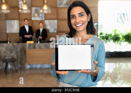 Hotel receptionist showing digital tablet with white mockup blank screen Stock Photo