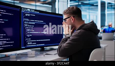 Tired Software Engineer Struggles With Coding Tasks At His Office Desk. Stock Photo