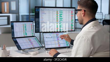 Young Healthcare Analyst Reviews Medical Billing Codes Using Dual Touchscreens. Stock Photo