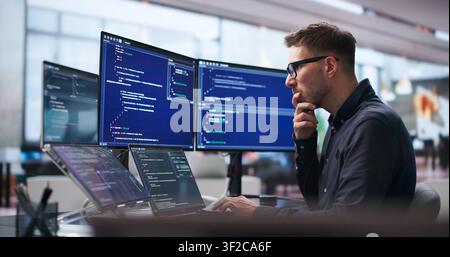 Young Software Engineer Uses Laptop And Touchscreen To Develop Secure Algorithms. Stock Photo
