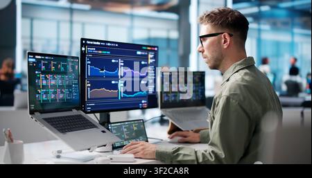 Young IT Specialist Monitors Real-time Network Data On Laptop Screen. Stock Photo