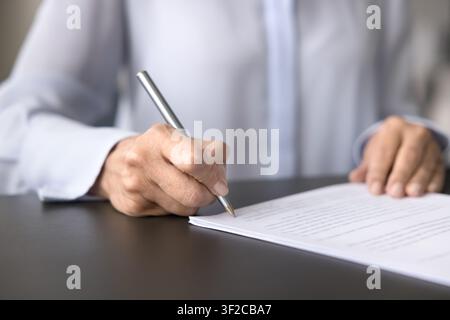 Female in white official shirt put signature on paper document Stock Photo