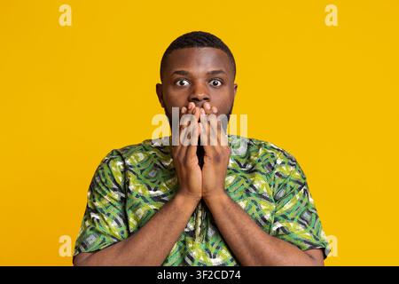 Shocked black man covering mouth with hands Stock Photo