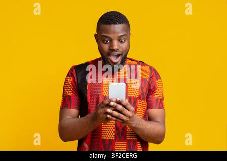 Amazed black guy looking at smartphone screen Stock Photo