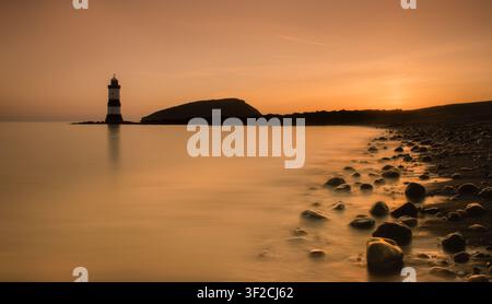 Penmon Lighthouse, Anglesey, North Wales. Tranquil sunrise with soft pastel colours over Puffin Sound and a calm Irish Sea. Stock Photo
