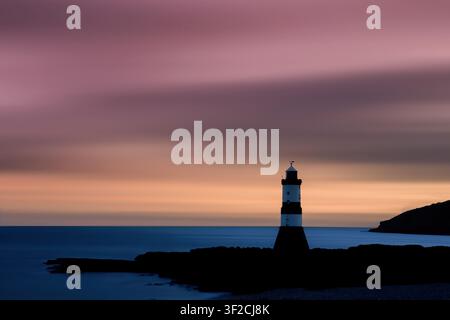 Penmon Lighthouse, Anglesey, North Wales. Tranquil sunrise with soft pastel colours over Puffin Sound and a calm Irish Sea. Stock Photo