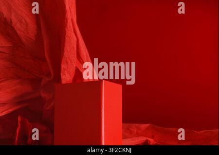 Empty red rectangular podium on dramatic red background with crumpled paper Stock Photo