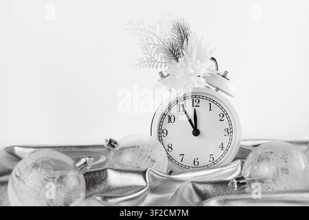 Christmas monochrome composition with silver draped fabric, holiday decorations and alarm clock on white background Stock Photo