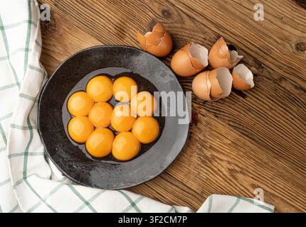 Egg Yolks in Bowl, 10 Fresh Chicken Egg Yolk Separated from Whites for Cooking Recipe, Ten Organic Yolks on Black Plate Stock Photo