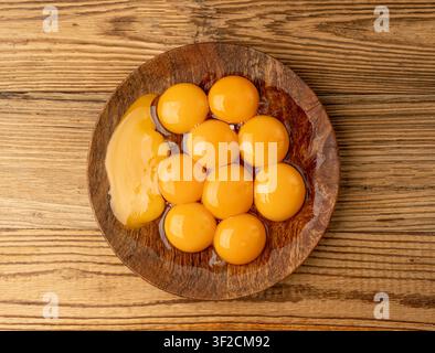 Egg Yolks in Bowl, Fresh Chicken Egg Yolk Separated from Whites for Cooking Recipe, Organic Yolks on Wooden Plate Top View Stock Photo