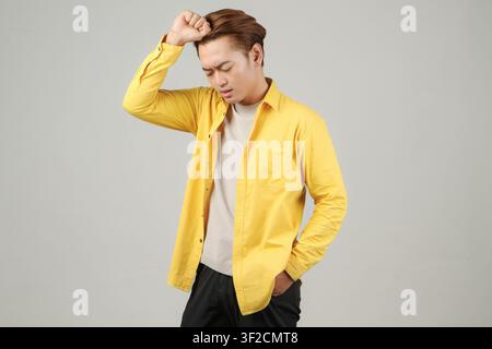 stressful expression of asian man wearing yellow casual outfit on isolated background Stock Photo