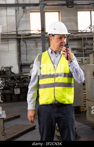 Factory supervisor communicating by two-way radio in manufacturing workshop Stock Photo