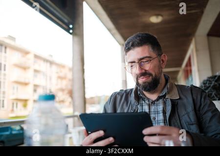 Man smiling, using tablet outdoors, working remotely with modern technology Stock Photo